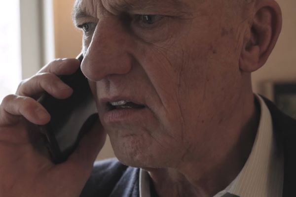 Äldre man pratar i telefon och ser förbryllad ut.