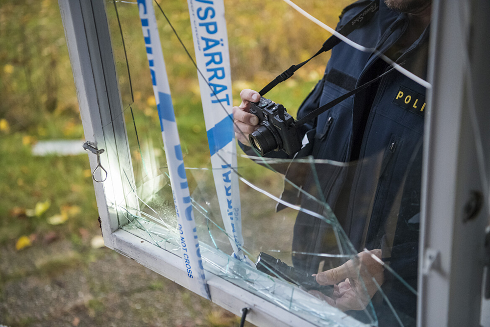 En polis säkrar spår på en krossad glasruta på en villa