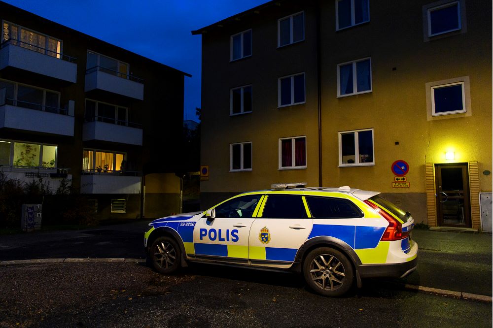 Polisbil med sirener parkerad utanför flerfamiljsbostadshus