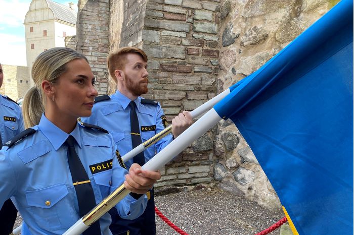 Foto av fanbärare som går i täten när polisaspiranterna tågar in på Vadstena slott.