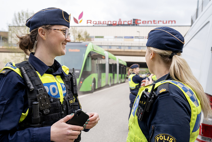 Två kvinnliga poliser vid en trafikkontroll med Rosengårds Centrum i bakgrunden