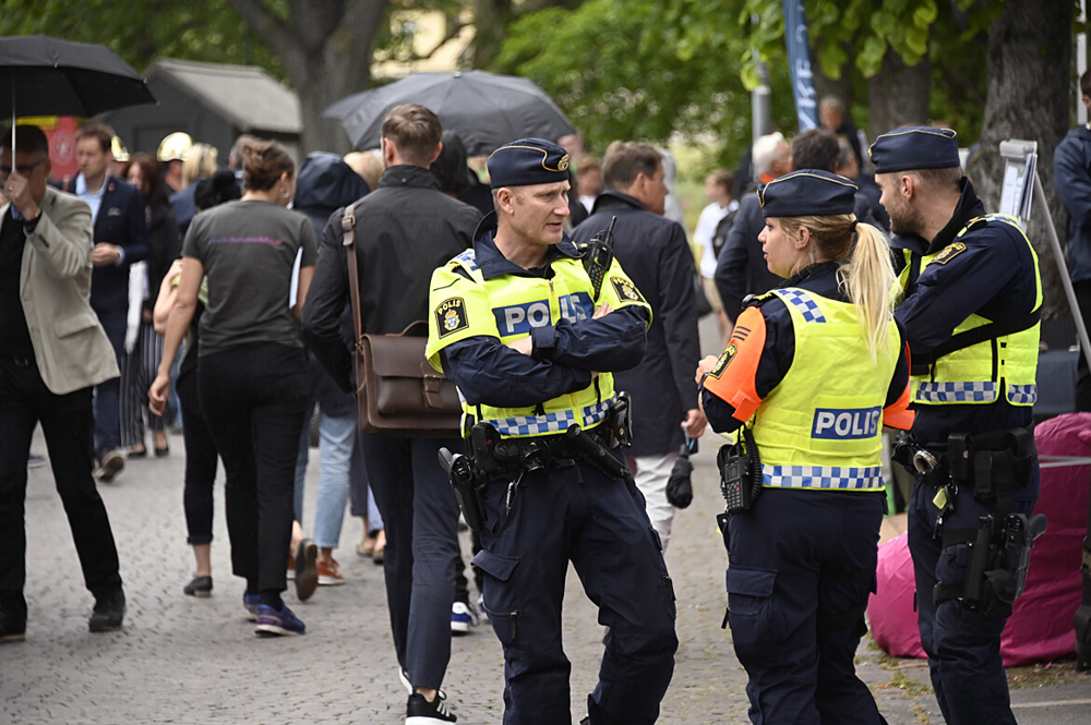 Tre poliser som står och pratar i en folksamling under almedalsveckan.