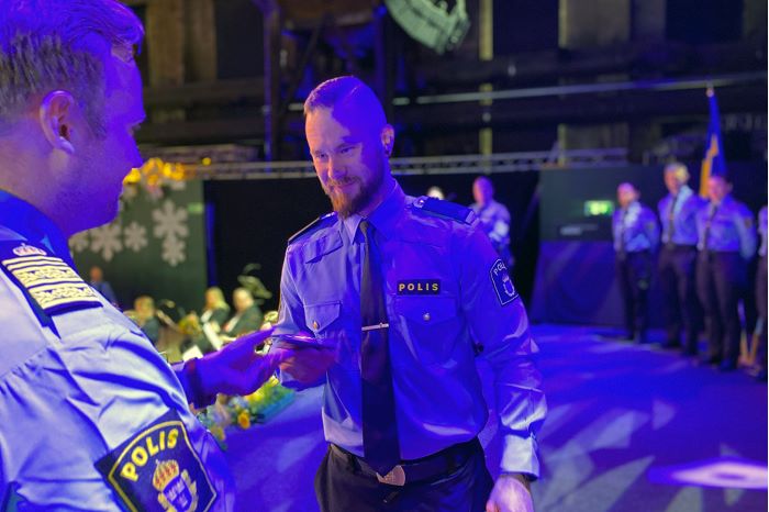 Fotografi som visar Mattias Forssten, polisområdeschef för Södermanland, när han delar ut axelklaffar till polisassistenterna.