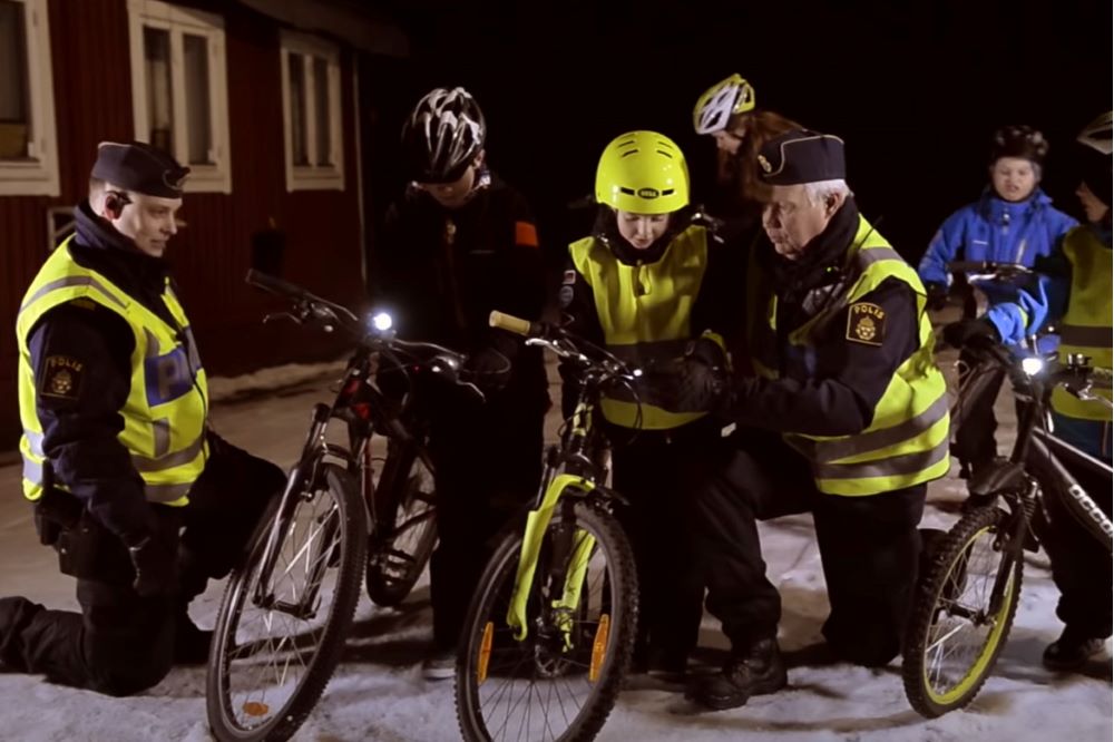 Två poliser som hjälper barn att ordna lampor på sina cyklar