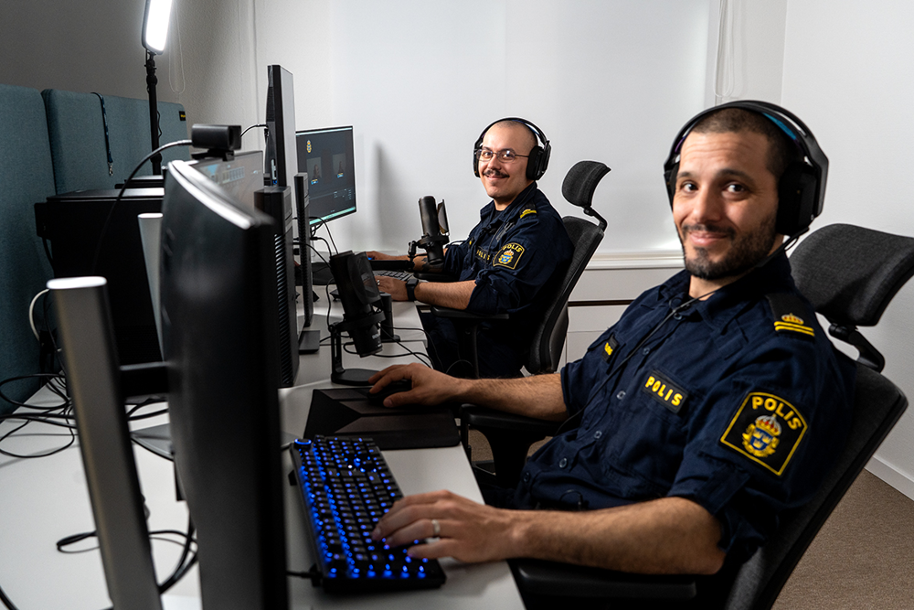 Två poliser som sitter framför datorn och spelar