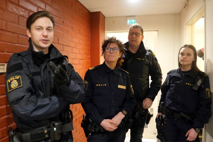 Fyra polisklädda personer står i en korridor
