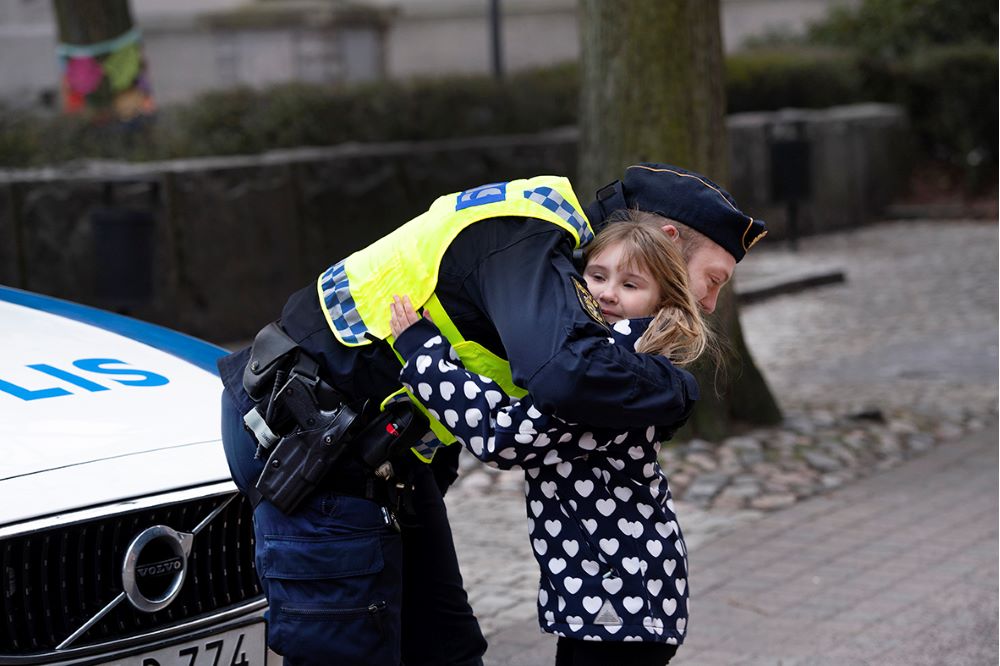Polis kramar ett barn. Foto.