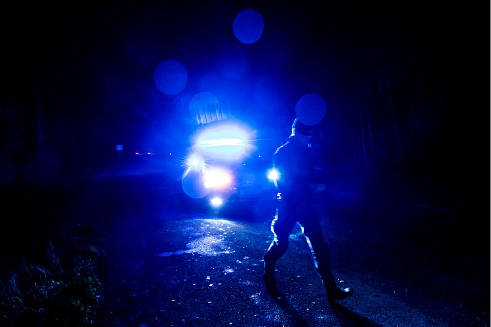 Polisbil med blåljus påslagna en mörk och regnig kväll.