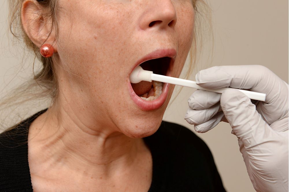 Fotografi av kvinnohuvud med en tops-pinne i munnen. Man ser inte ansiktet på kvinnan.