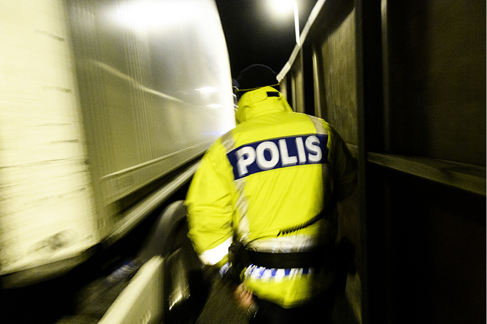En polis kommer gående mot en lastbil och det är mörkt ute.