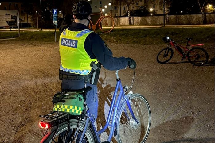 Polis med cykel ute under kvällstid.