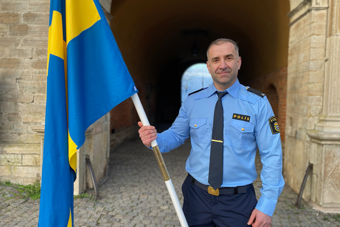 En manlig polis bär fanan och tittar mot kameran. 