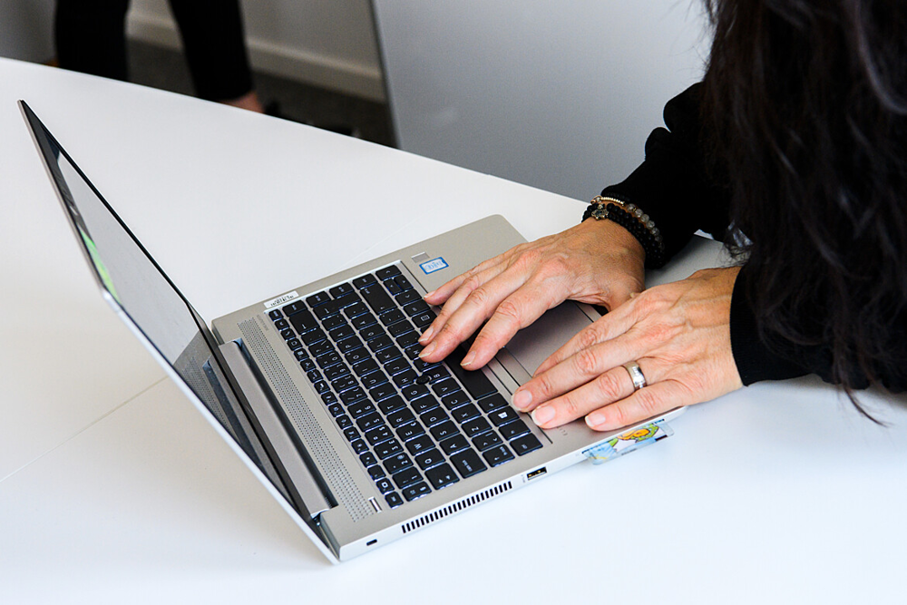 Närbild på laptop där en kvinnas händer skriver på tangentbordet