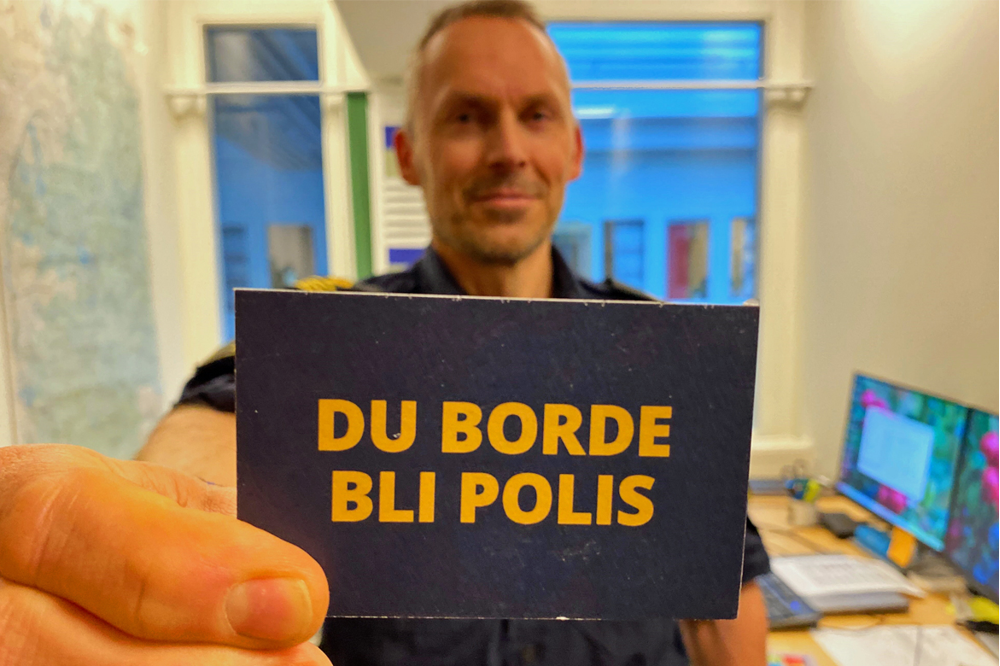 Ett kort med texten Du borde bli Polis hålls i av en manlig polis