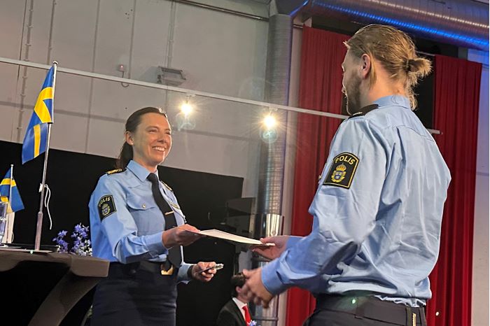 En polisassistent tar emot diplom och nya axelklaffar från regionpolischef Malena Grann.