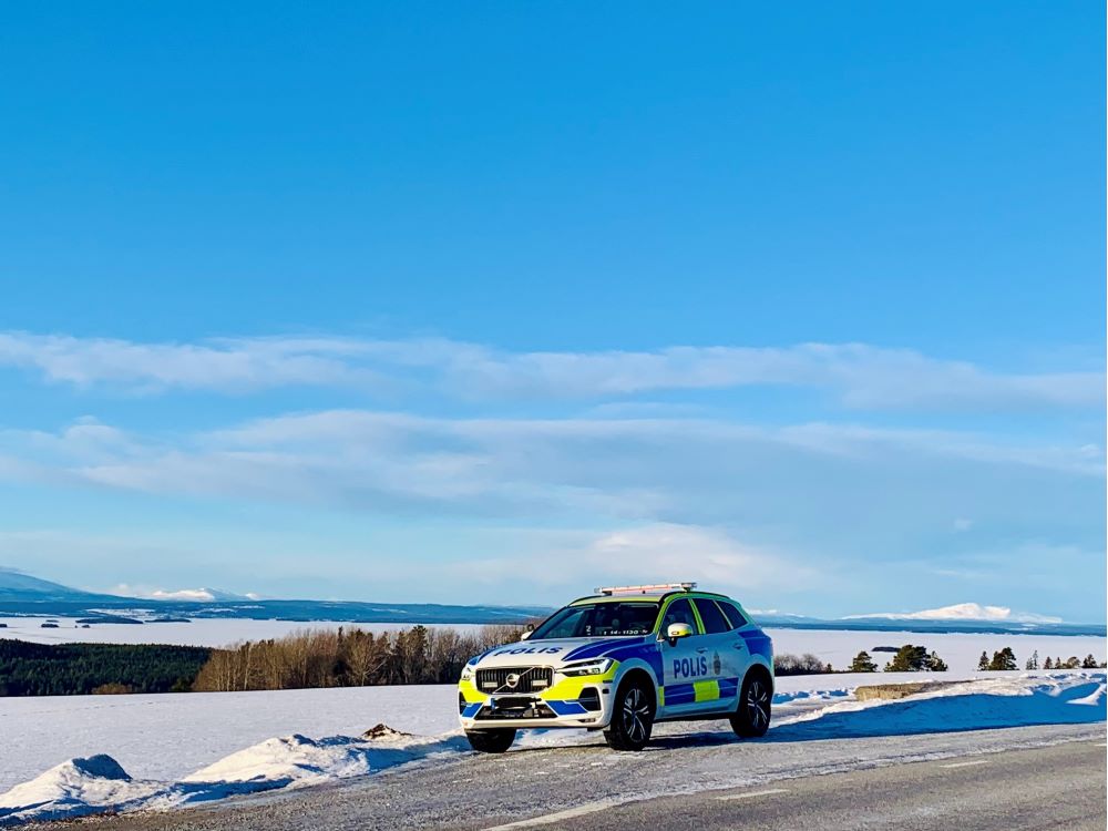 Målad polisbil på en väg med fjäll i bakgrunden i vintermiljö