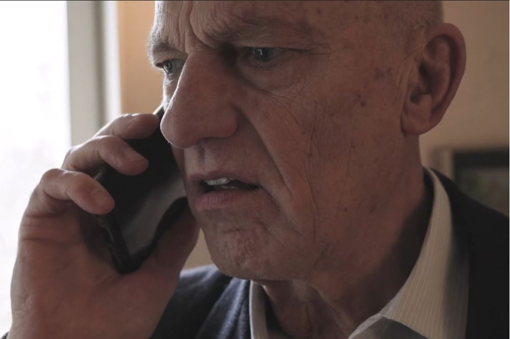 Äldre man talar i telefon och ser förbryllad ut.
