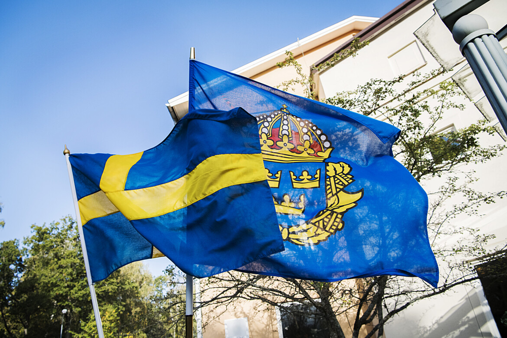 Polisflaggan och svenska flaggan vajar i vinden