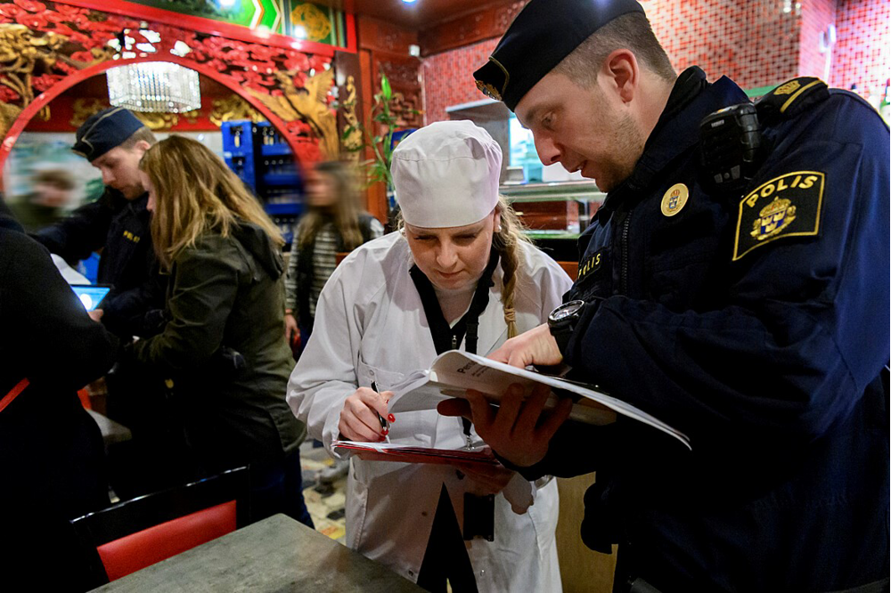 En manlig polis och en kvinnlig kock i restaurangmiljö.