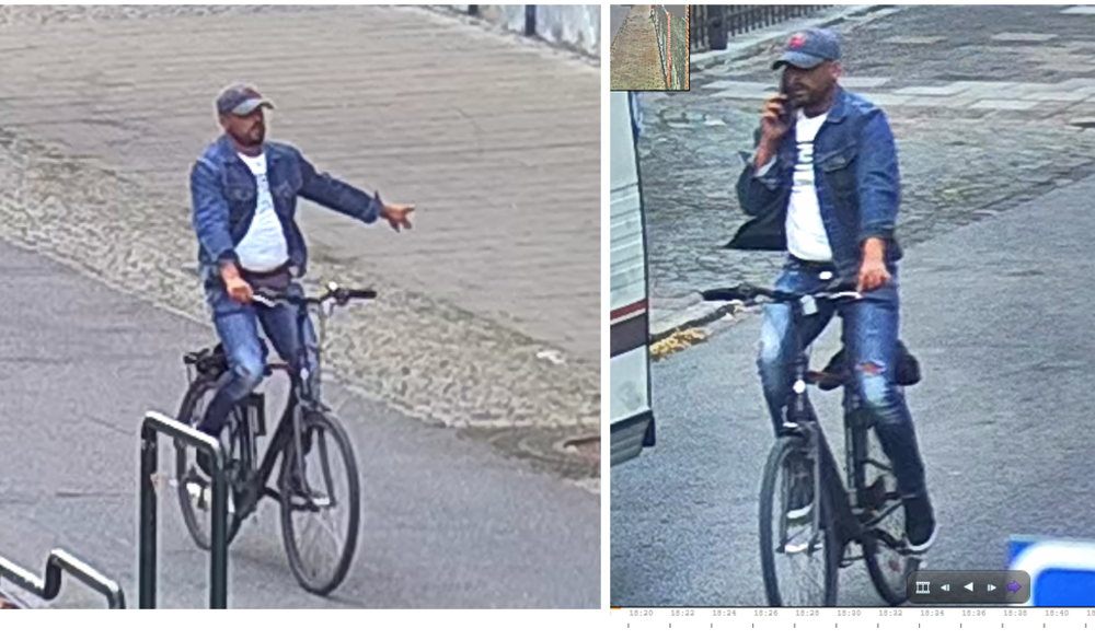 Man på svart cykel iklädd jeans, vit t-shirt, jeansjacka och blå keps.