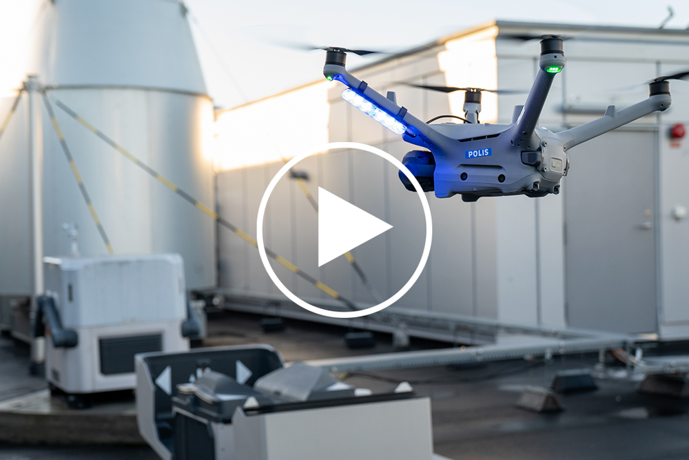 En drönare lyfter ur en låda. En play-knapp visar att det är en film.