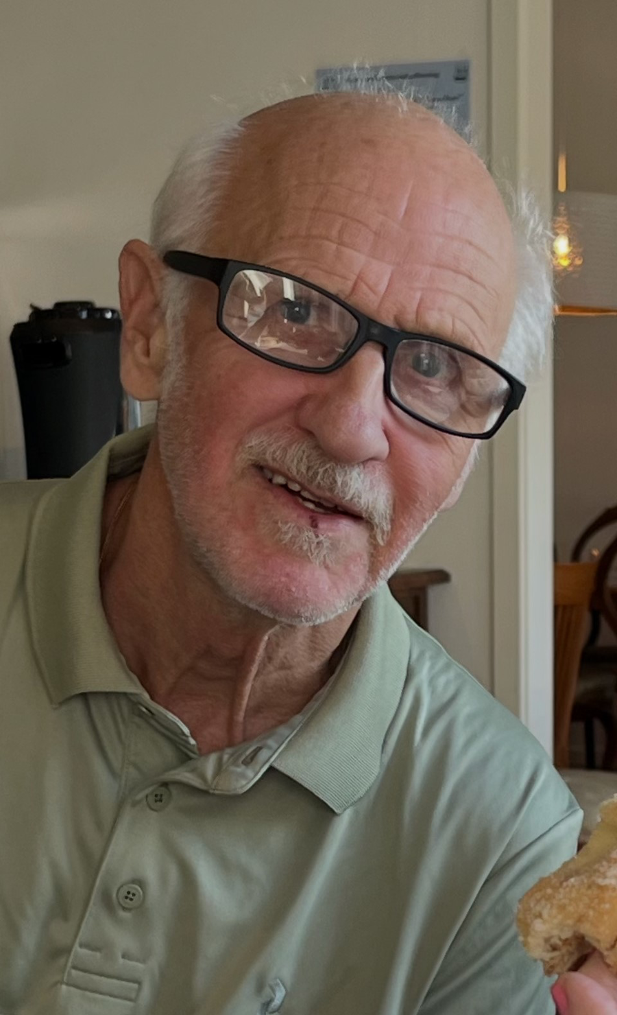 Porträttbild på man med vitt hår och svarta glasögonbågar