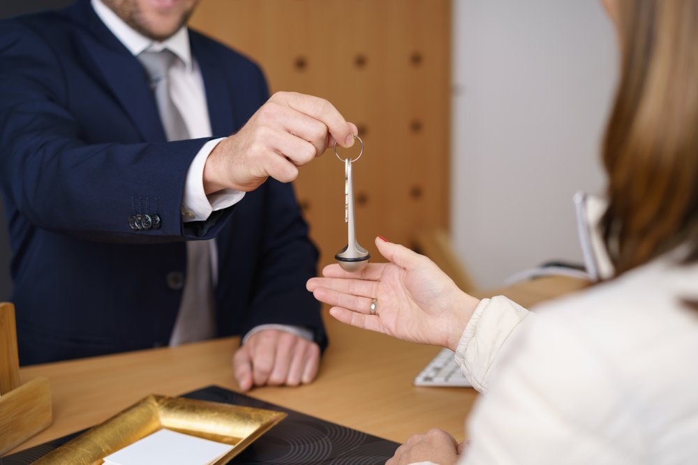 Hotellreceptionist räcker över en nyckel till en kvinna över en disk.