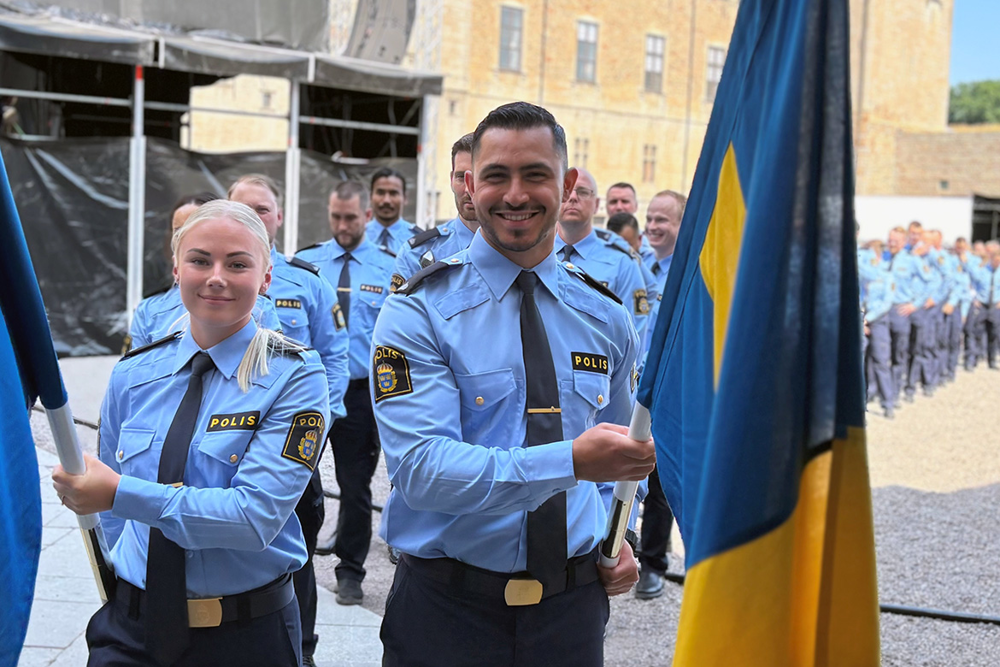 Nyutexaminerade poliser i ett långt led med två fanbärare i fokus