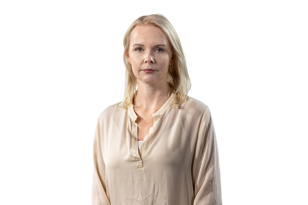 En kvinna står framför en vit bakgrund.