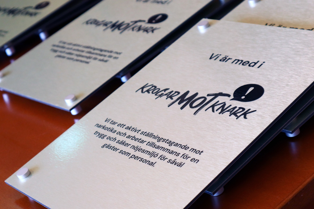 Fotot visar det budskap som krogarna sätter upp i sina lokaler. Texten lyder: Vi är med i Krogar mot knark. Vi tar ett aktivt ställningstagande mot narkotika och arbetar tillsammans för en trygg och säker nöjesmiljö för såväl gäster som personal".