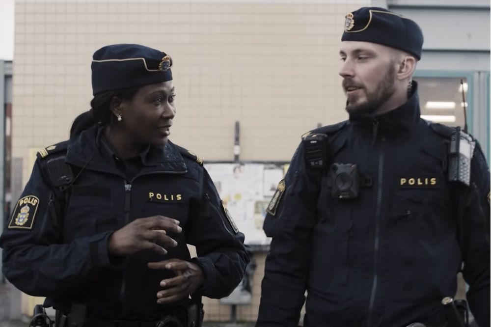 Skärmdump från filmen: Två poliser pratar under en promenad utomhus
