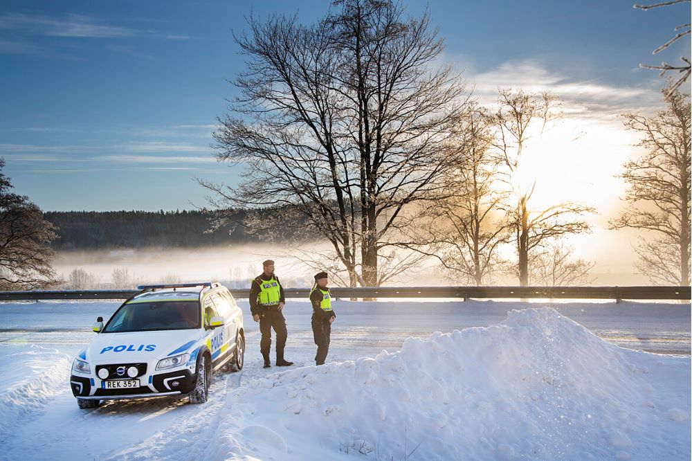 Polisbil och två poliser står i ett vinterlandskap