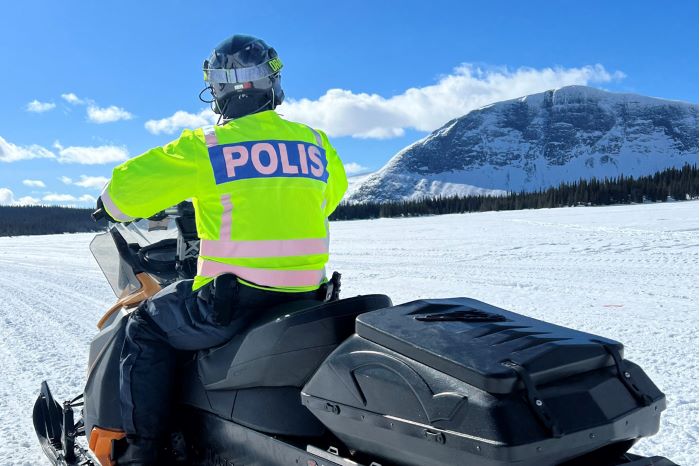 Skoteråkande polis i fjällmiljö och sol