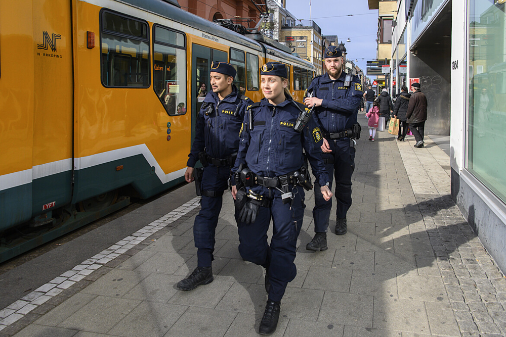 Tre poliser som går på en gata.