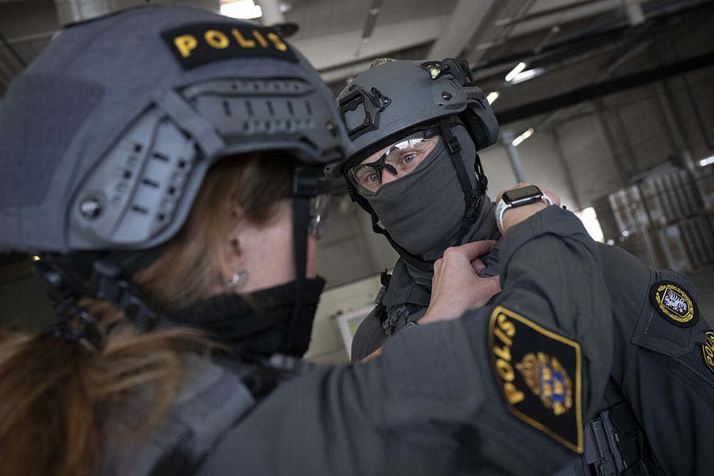 Två poliser med grå hjälmar står mitt emot varandra.