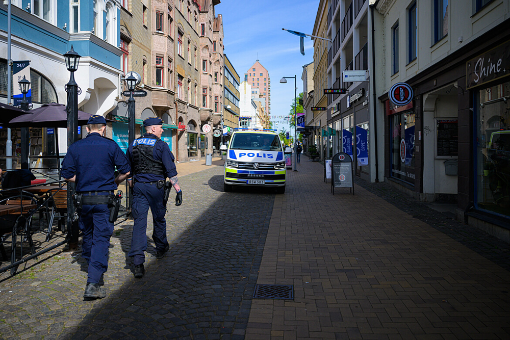 Två poliser går på en gågata med affärer