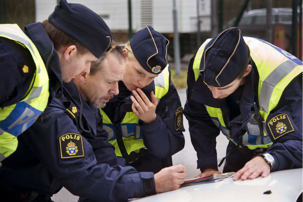 Poliser som står lutade över en karta