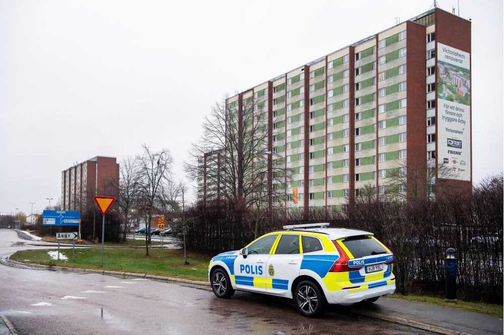 Fotografi som visar en polisbil som är parkerad framför flerfamiljshus i bostadsområdet Årby i Eskilstuna