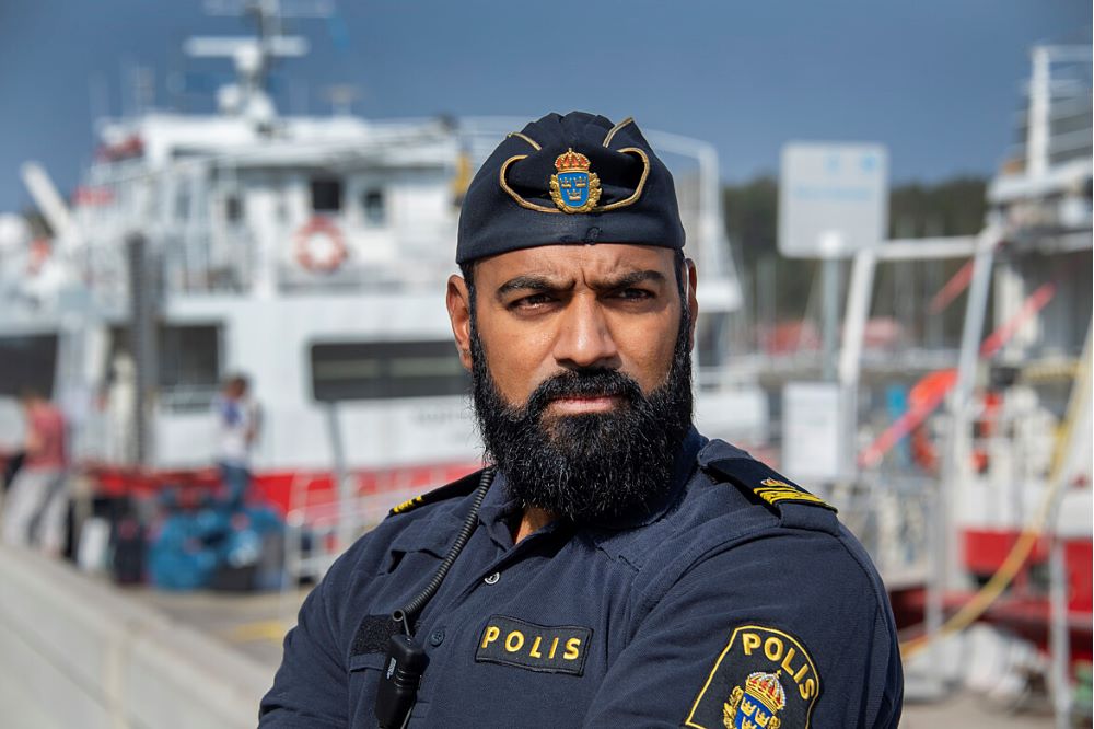 Polis i uniform med båtar i bakgrunden