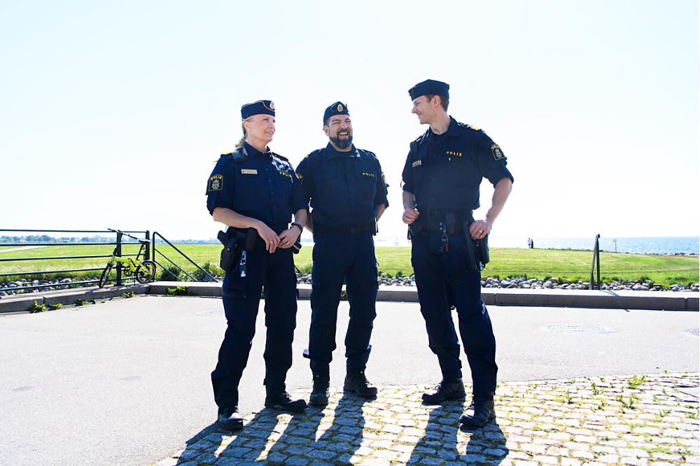 Tre poliser som står i bakgrunden