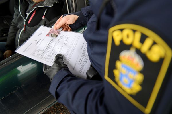 Polis som kontrollerar covid-intyg vid gräns till Sverige.
