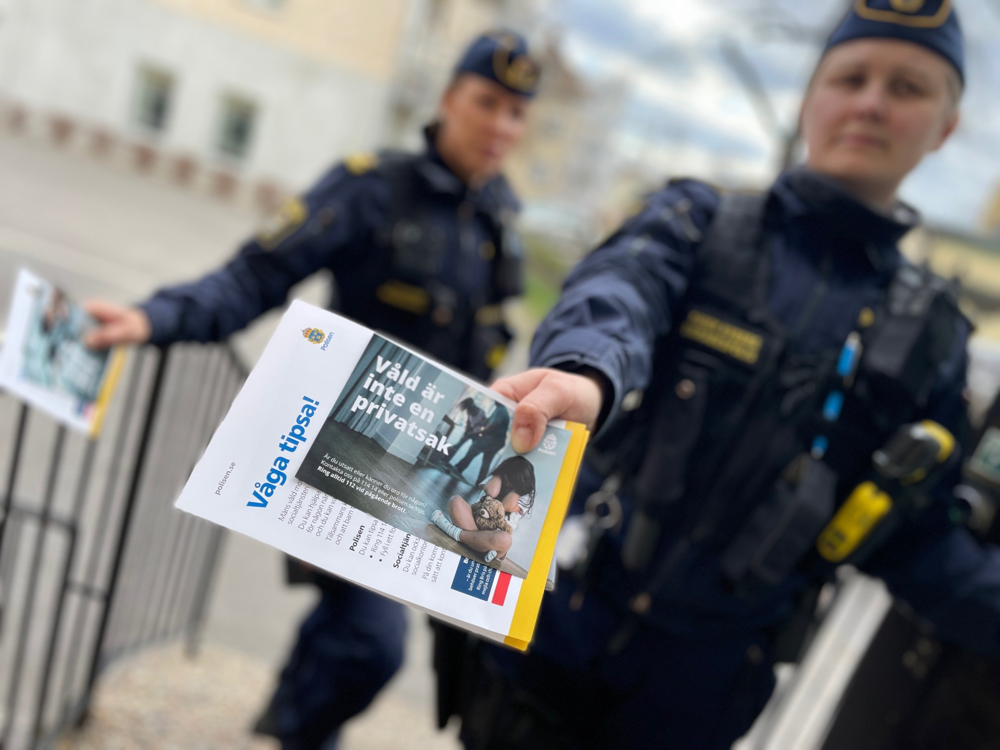 Ett fotografi som visar två kvinnliga poliser som står utanför en lägenhetsdörr och pratar med lägenhetsinnehavaren.