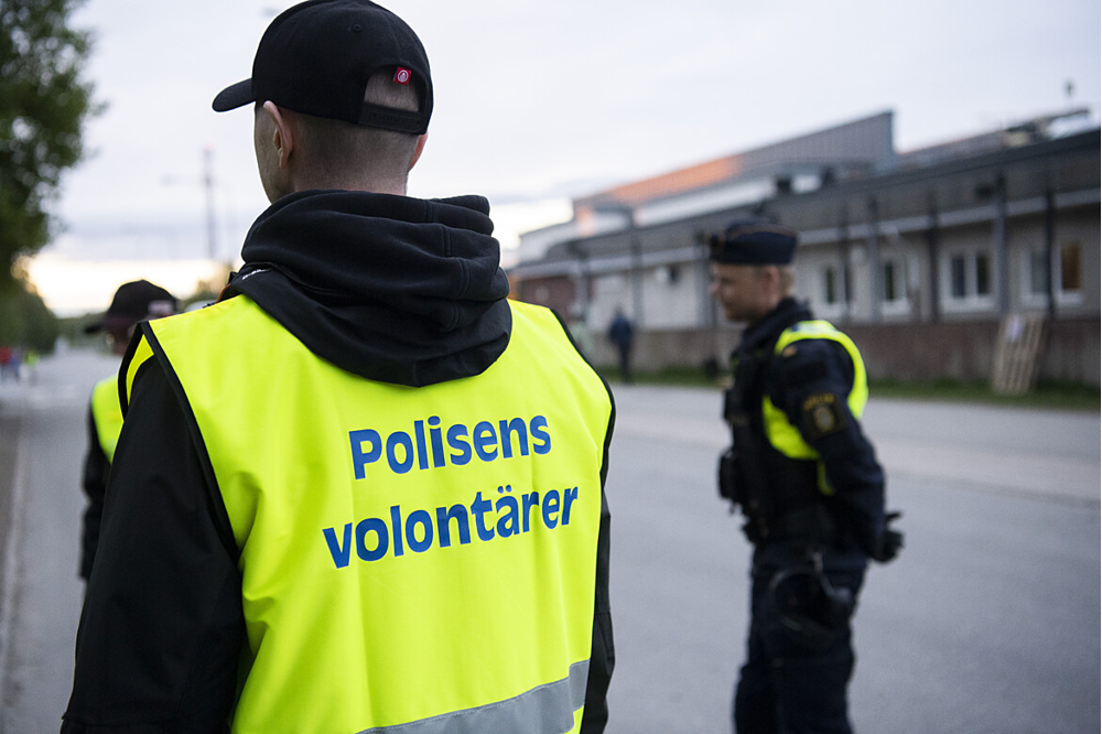Person utomhus med gul väst med texten Polisens volontärer