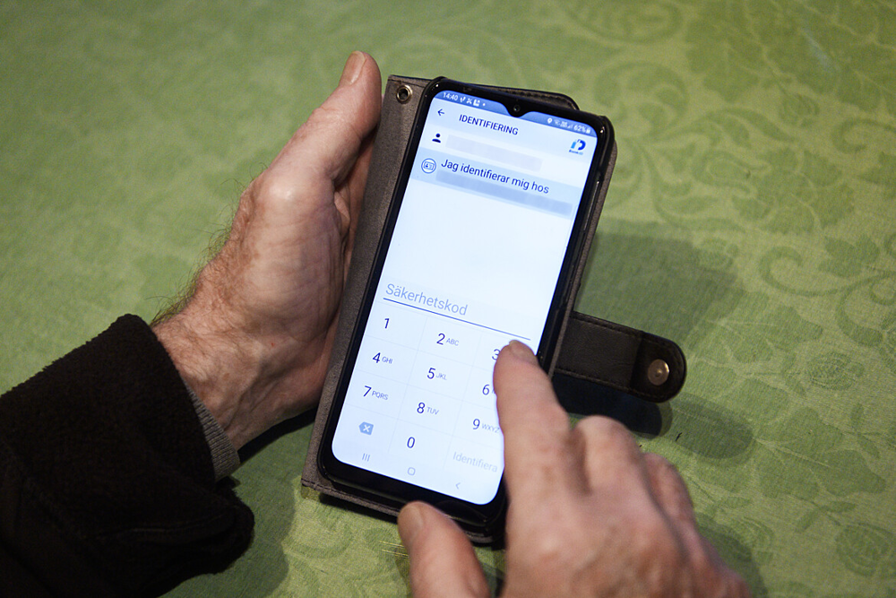 Pensionärs händer som håller en mobil.