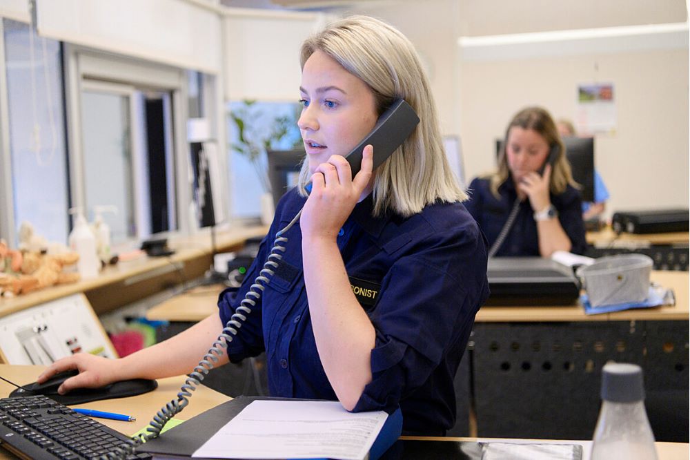 Uniformsklädd kvinna som talar i telefon med ett tangentbord framför sig.