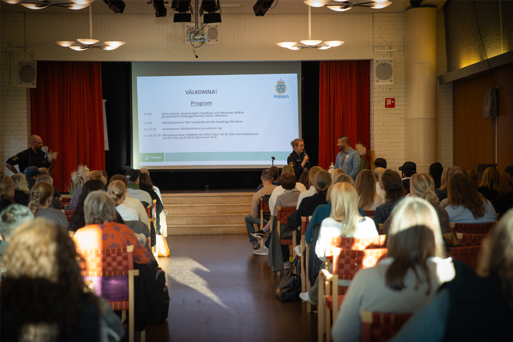Foto på Anna Schelin och Alexander Drikha som står framför publik och välkomnar dem till informationskvällen.