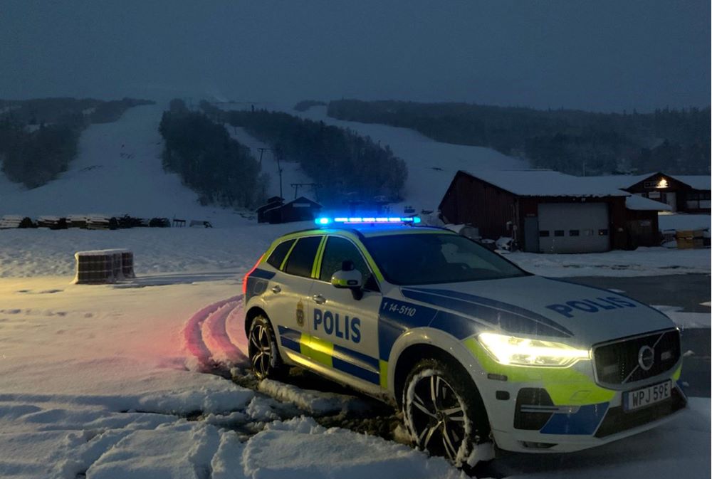 Polisbil parkerad i Åre i skymningen med skidbacke i bakgrunden