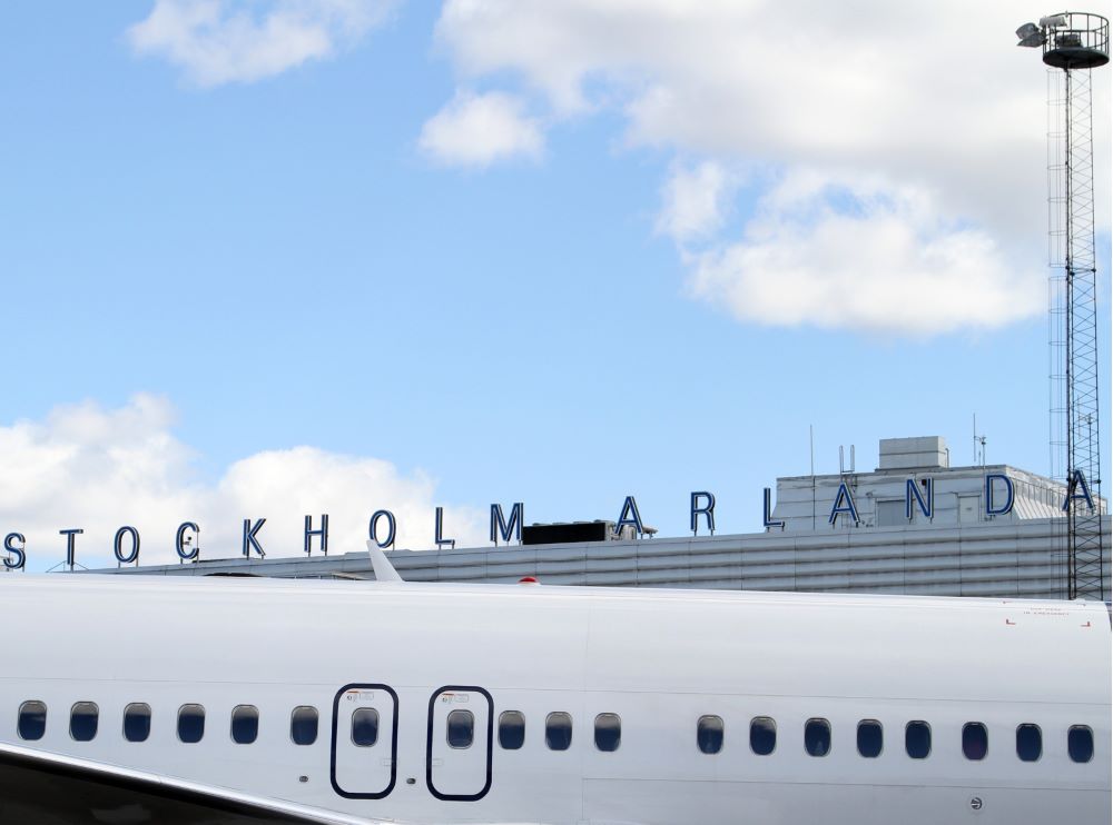 Överdel av flygplan framför skylt med texten "Stockholm Arlanda".