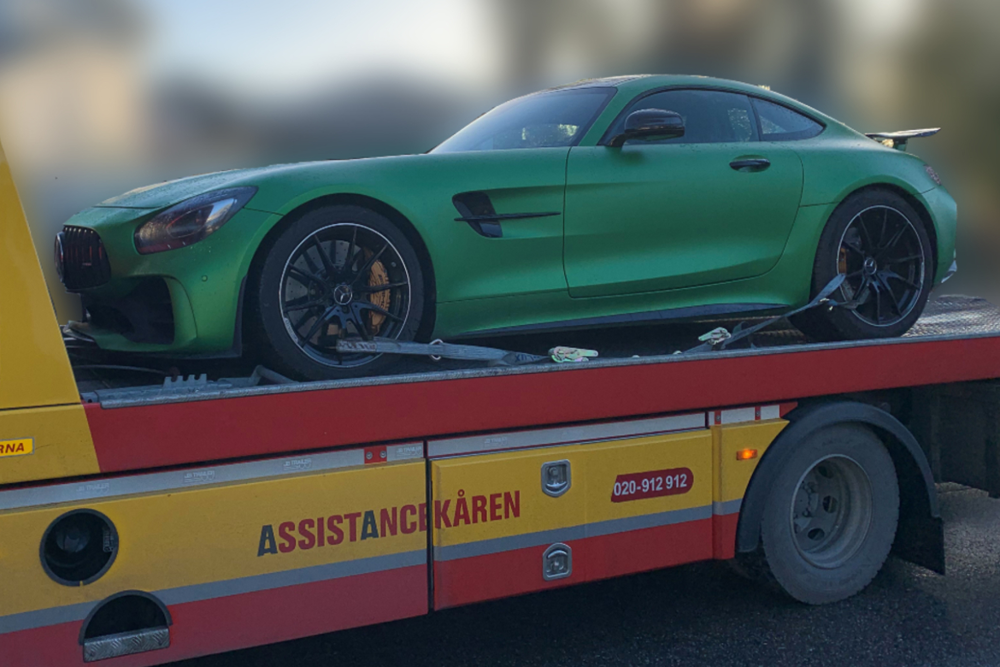 En grön bil är på en bärgningsbil.