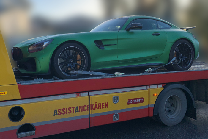 En grön bil är på en bärgningsbil.